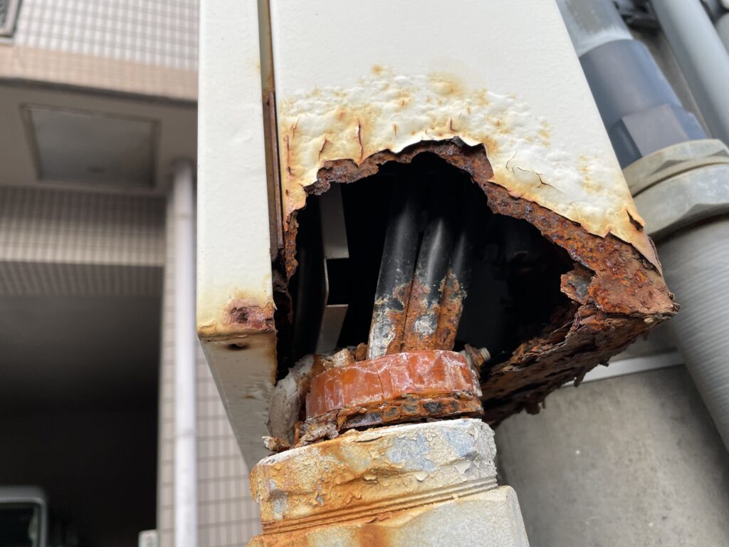 配電盤の塗装を先送りした場合の例。筐体の下部が腐食して穴が開き、内部の配管や配線が見えている状態