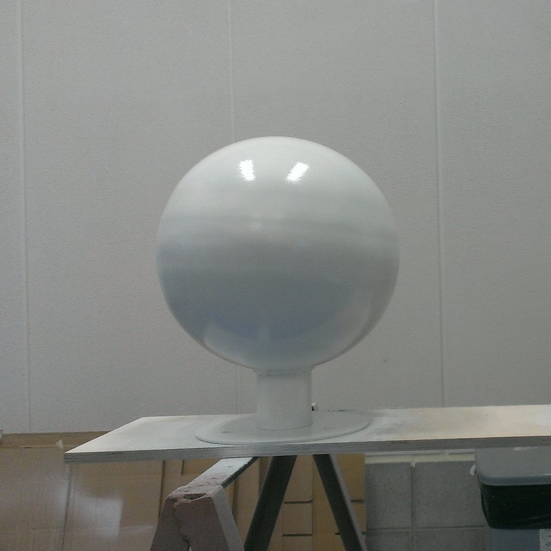 施工中の装飾球（スチール製）。金色の仕上げに入る前に、下塗りを重ねている段階の白い球面
