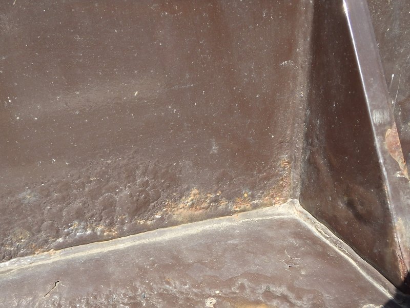 塗膜の剥がれ・膨れ・点錆|屋外設備の架台の下端で塗膜の下の錆が進み、膨れと錆が出た状態