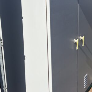 施工中、補修を終えた屋外キュービクルの扉と側面を、全面にグレーで塗り重ねている途中の段階